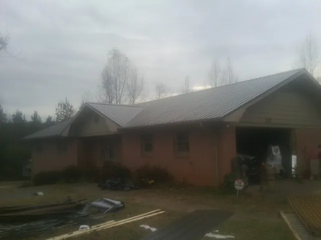 Gray metal roof on a stucco house with an attached garage in East Granby