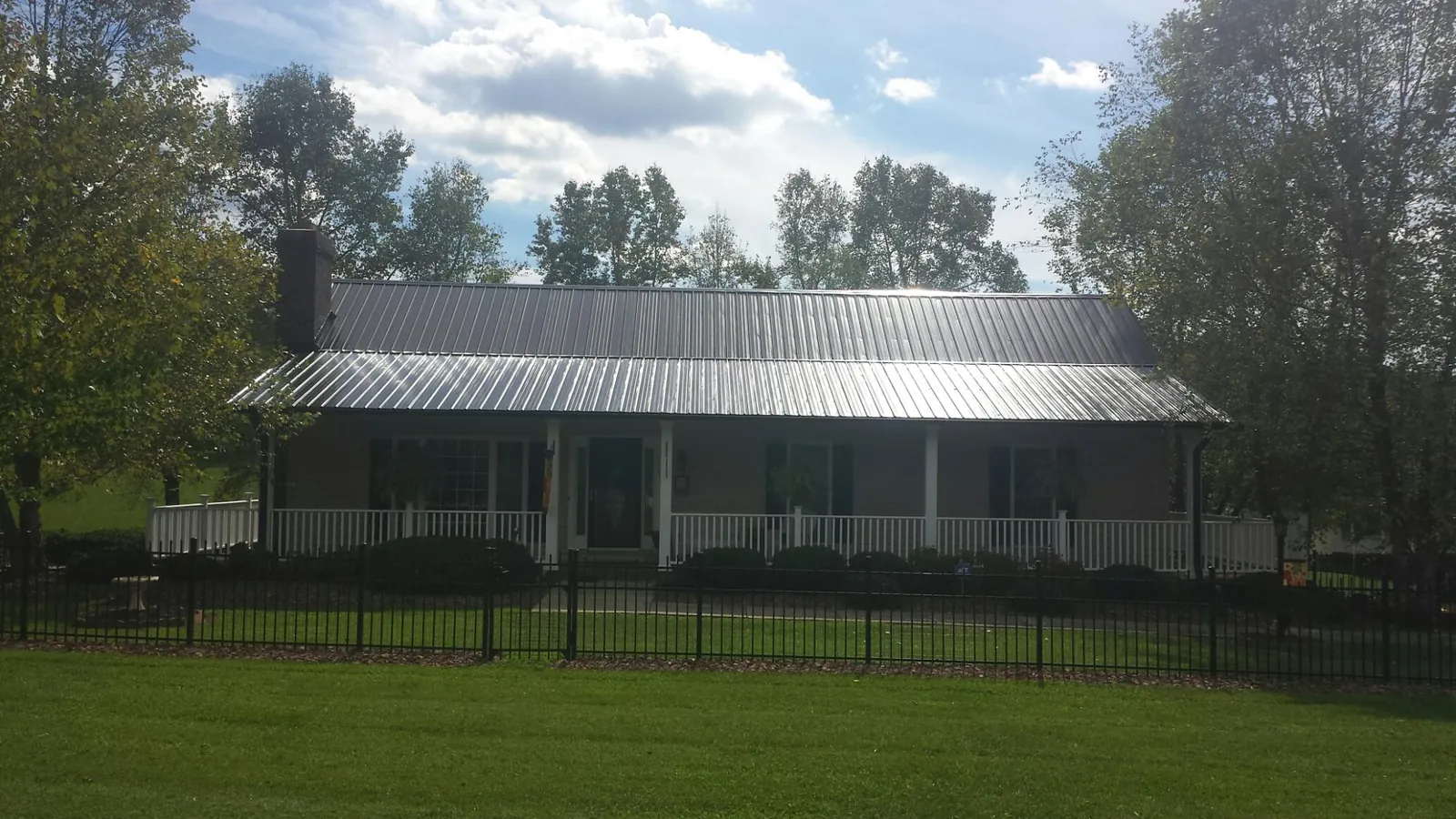 Gray metal roof on a brick ranch with a full width front porch — Gutter Guard Installation work by our crew in East Granby