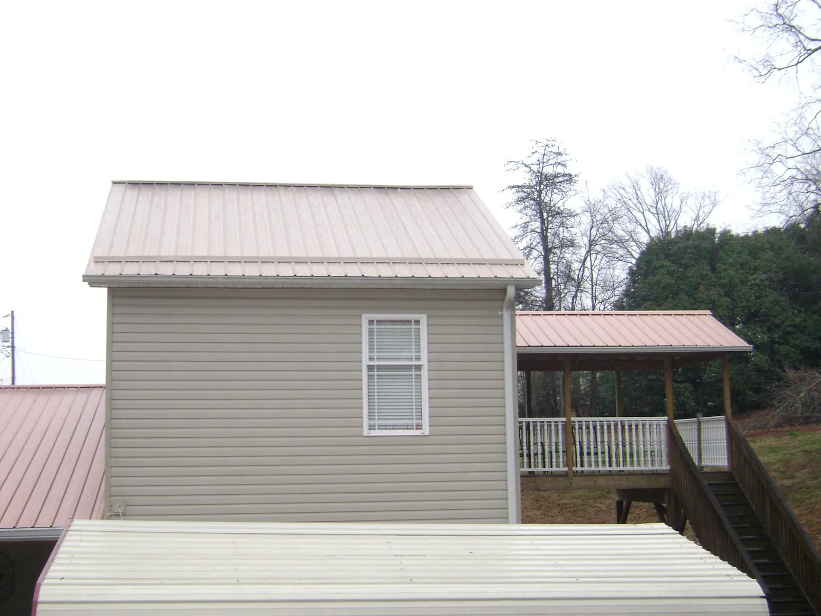 Tan metal roofs on a two story addition and attached porch, from a Roof Replacement job in East Granby