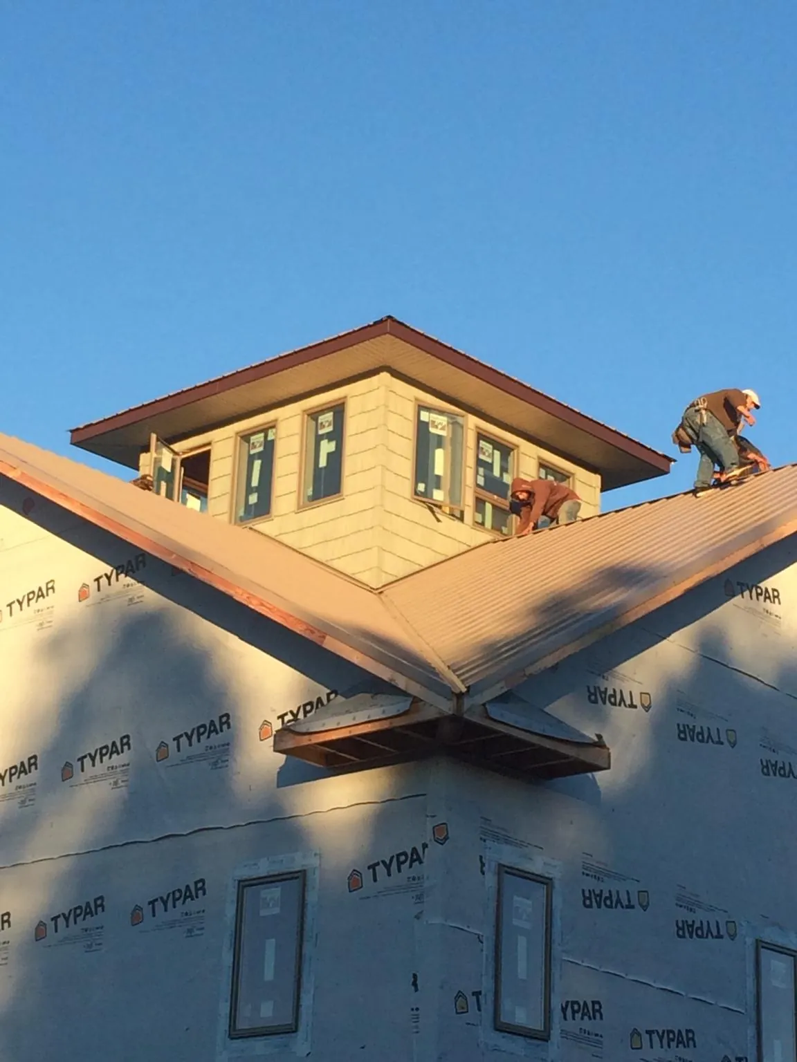 Roofers working around a rooftop cupola on a new metal roof at sunset — Roof Waterproofing in East Granby by Roofing Brothers